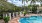 a pool with a deck and chairs by it and trees around it