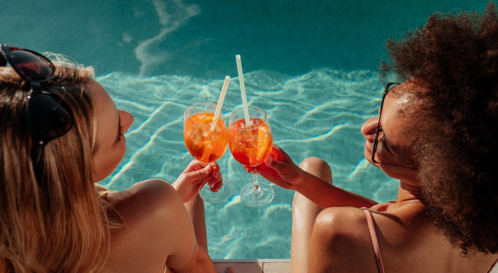 Relax and unwind poolside a two women drinking from glasses at a pool