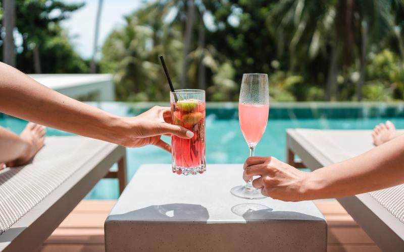 two people with a couple of drinks on a table at a pool