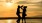 a man and woman holding dancing on a beach at sunset